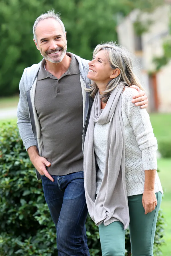Bioidentical-Hormone-Therapy-Treatment A mature couple in gray toned clothes and jeans walk happily outside, happy with their successful bioidentical hormone treatments from Dr. Robert Powers of Eternal Vitality Orlando in Orlando.