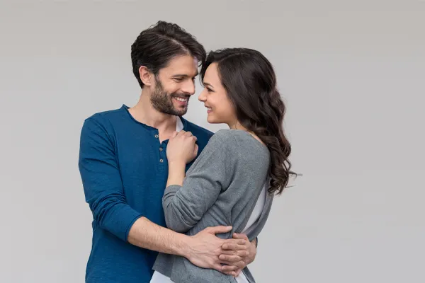 Erectile-Dysfunction-Doctor A man in a blue shirt embracing a woman in a gray shirt smiles due to his successful erectile dysfunction care from Dr. Robert Powers of Eternal Vitality Orlando in Orlando.