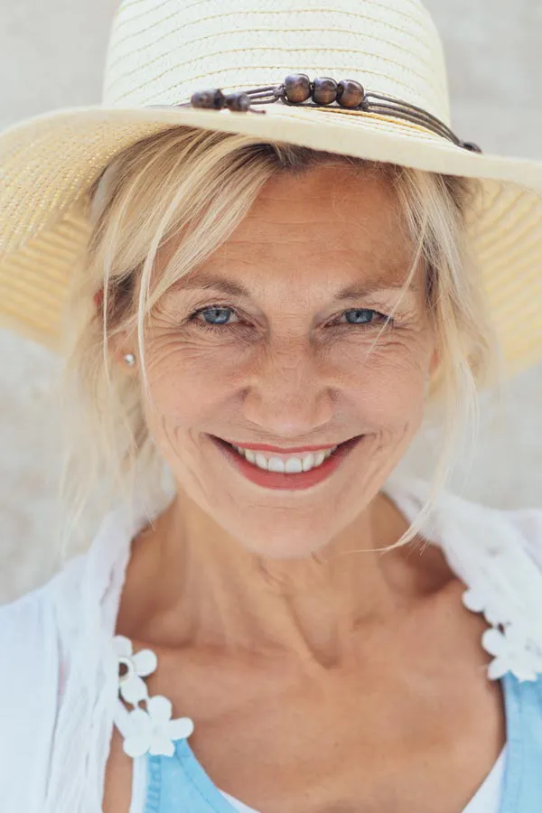 Menopause-Treatment A beautiful, smiling older woman with blonde hair and a sunhat, happy with menopause treatment from Dr. Robert Powers of Eternal Vitality Orlando in Orlando.