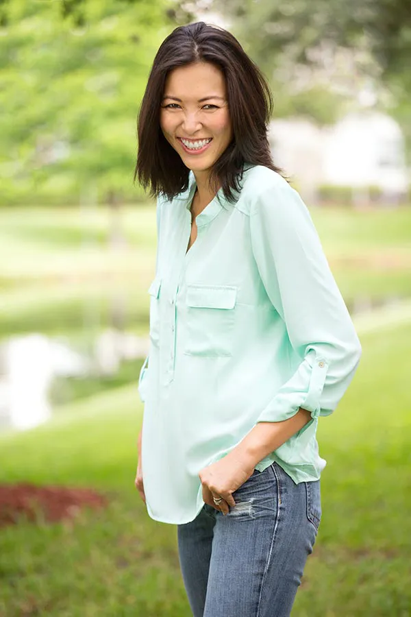 Perimenopause-Treatment A middle-aged brunette woman in a light green button-up shirt stands outside smiling, happy with her perimenopause treatment from Dr. Robert Powers of Eternal Vitality Orlando in Orlando.