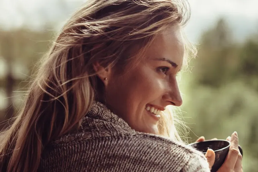 Womens-Health-Clinic A woman in a sweater looks out at the morning forest and smiles. Visit Women's Health expert Dr. Robert Powers of Eternal Vitality Orlando in Orlando.